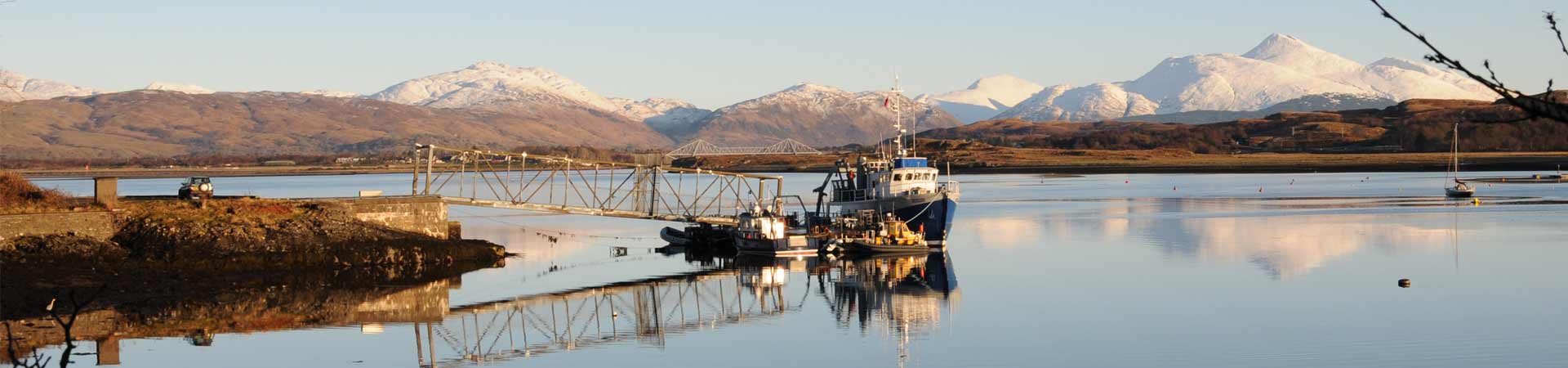Research vessels moored on SAMS pontoon with crisp mountains in background