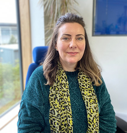 Photo of Sine MacKay taken at her desk in the enterprise office