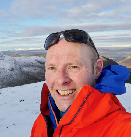 Head and shoulder selfie of Phillip Thompson in snowy mountain terrain in Scotland