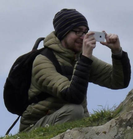 Pedro Morua on fieldwork taking photos of seaweed on his phone