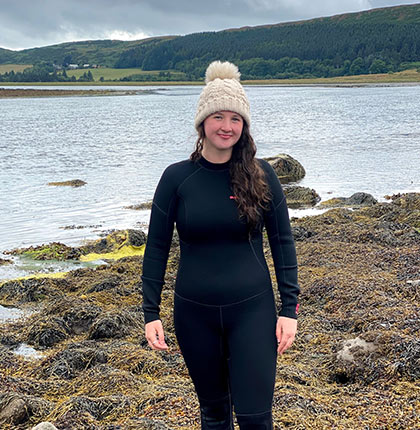 
        Caitlin Lamb on a beach wearing a wetsuit
        