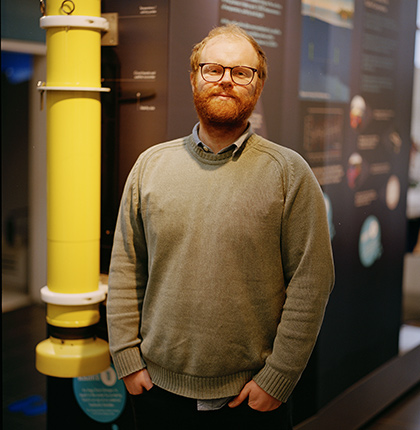 
        Head and shoulder shot of physical oceanographer Neil Fraser outside with research vessel behind
        