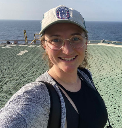 Smiling female consultant in baseball cap aboard large research vessel