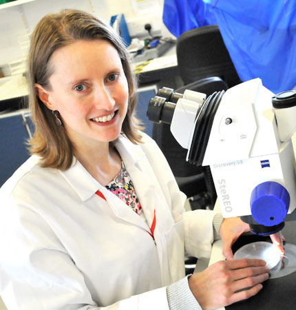 Rachel Allen wearing white lab coat working on a microscope