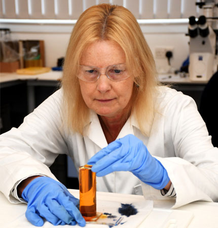Photo of Sarah Swan in lab coat and safety goggles conducting a chemical water analysis