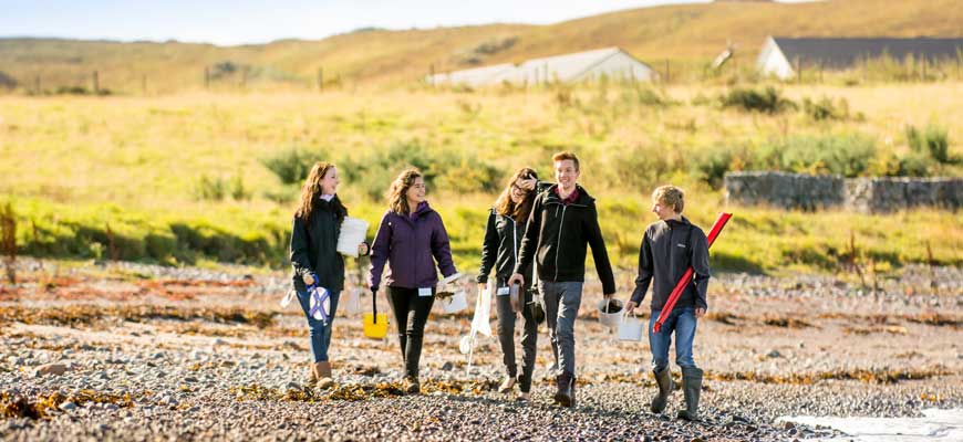 Students walking on the beach with sampling equipment