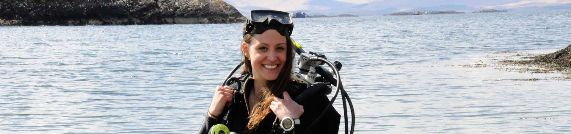 Undergraduate student with diving gear emerging from the Lynne of Lorn behind the laboratory