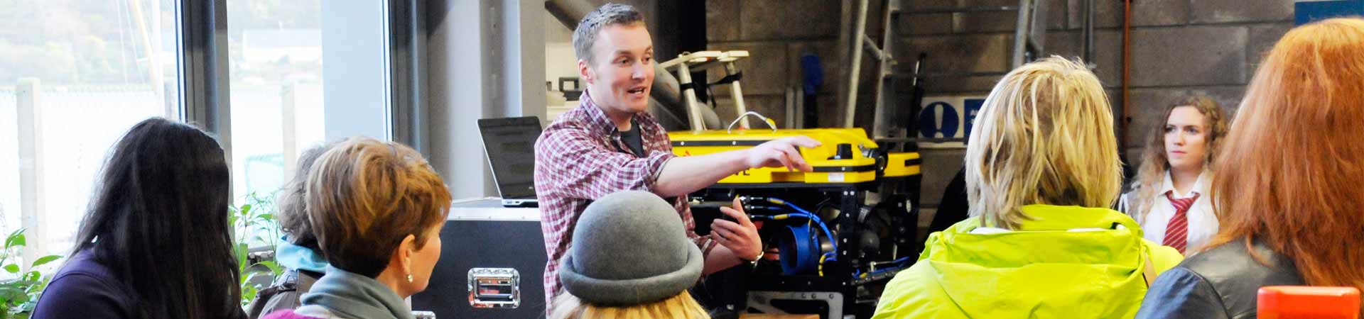 Image shows lecturer in our Scottish Marine Robotics Facility showing students different robots used in the marine environment