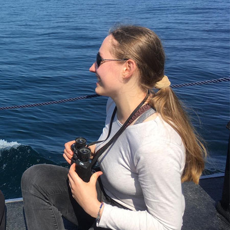Marine science undergraduate student Anna with binoculars out at sea